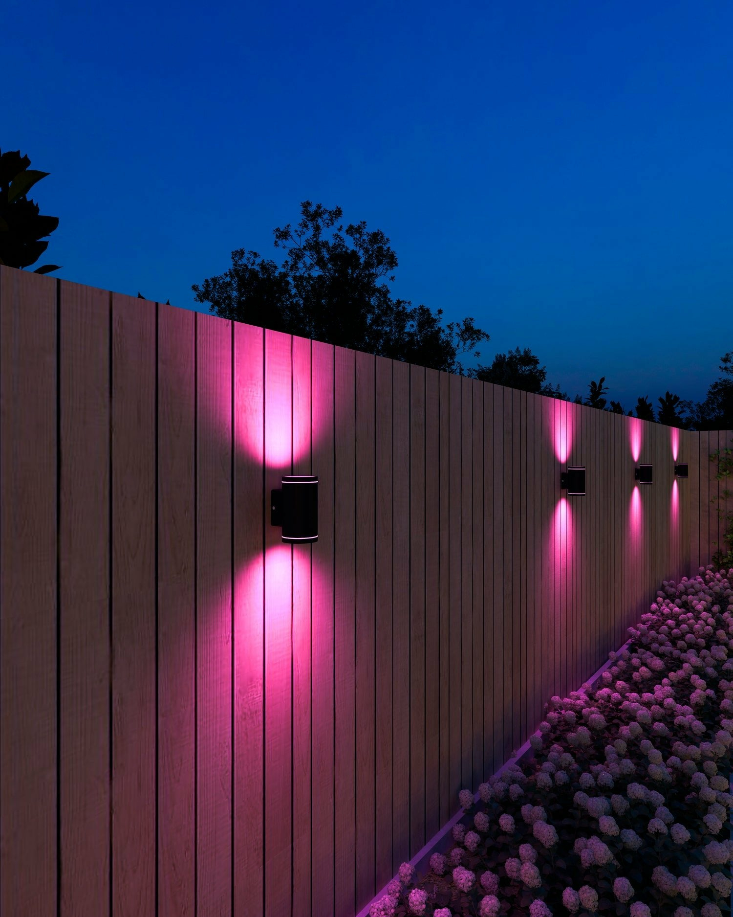 Appliques da parete per esterni con luce rosa che brilla su una staccionata di legno e fiori.