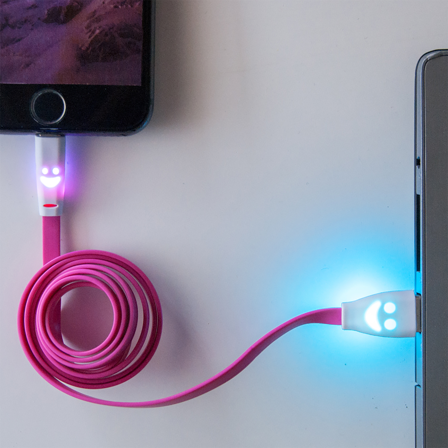 Un cavo di ricarica rosa collegato a un telefono, con una faccina sorridente a ogni estremità.