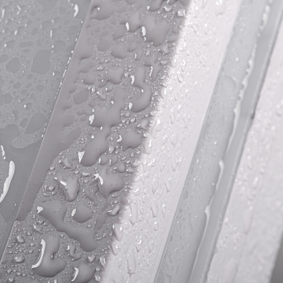 Waterdruppels op een grijs, geribbeld oppervlak, close-up shot.
