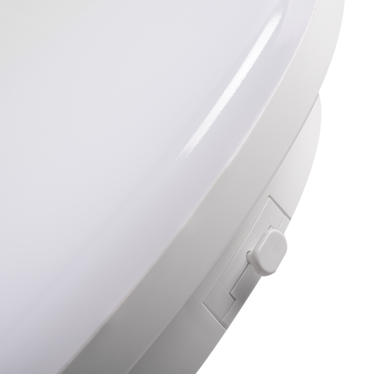Primo piano di un apparecchio di illuminazione bianco e circolare con un piccolo interruttore bianco sul lato.