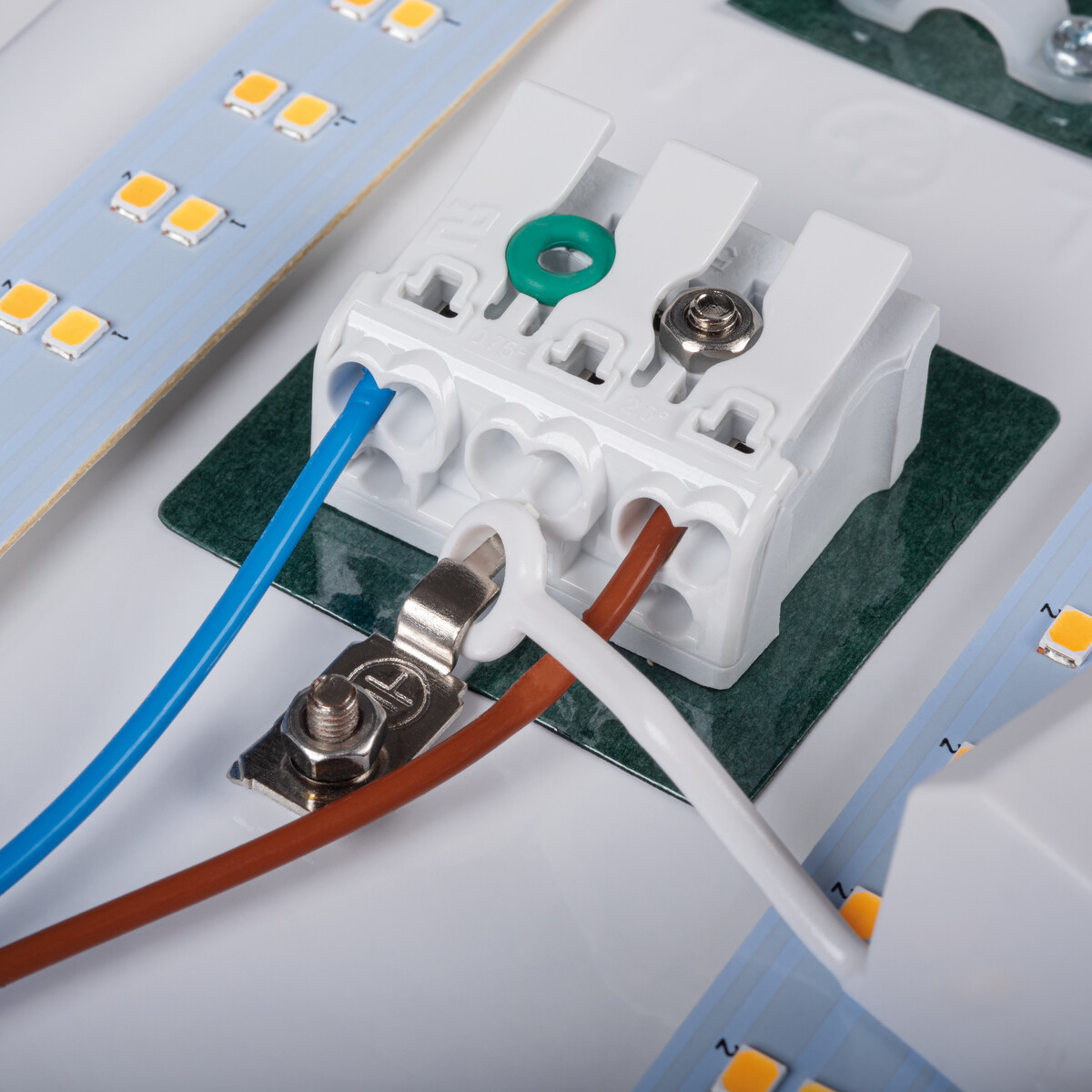 Primo piano di connettori elettrici e fili su una superficie bianca, con strisce LED visibili.