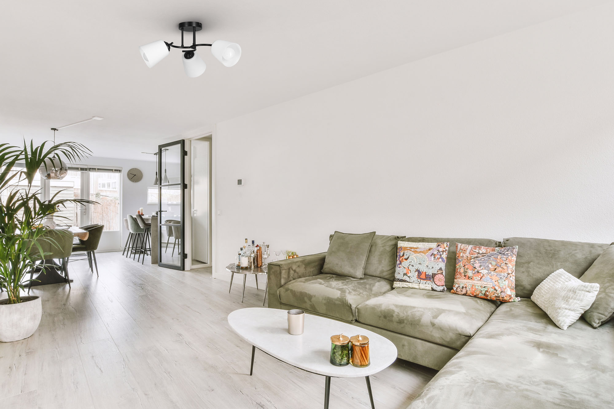 Un salón moderno con un sofá gris y una mesa de centro blanca. Una lámpara de techo cuelga encima.