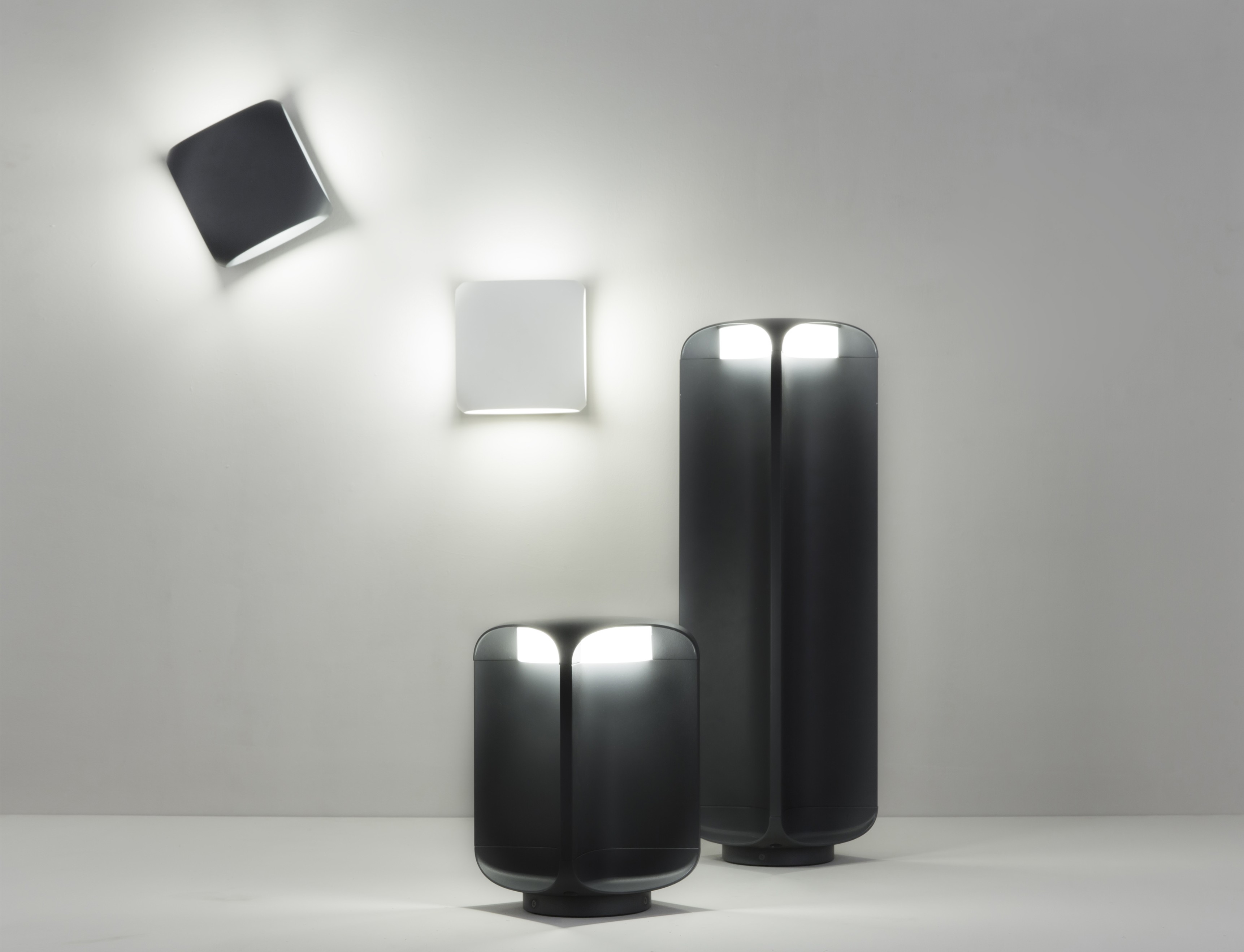 Collezione di lampade. Tre lampade grigio scuro con una parete bianca. Lo sfondo è bianco.