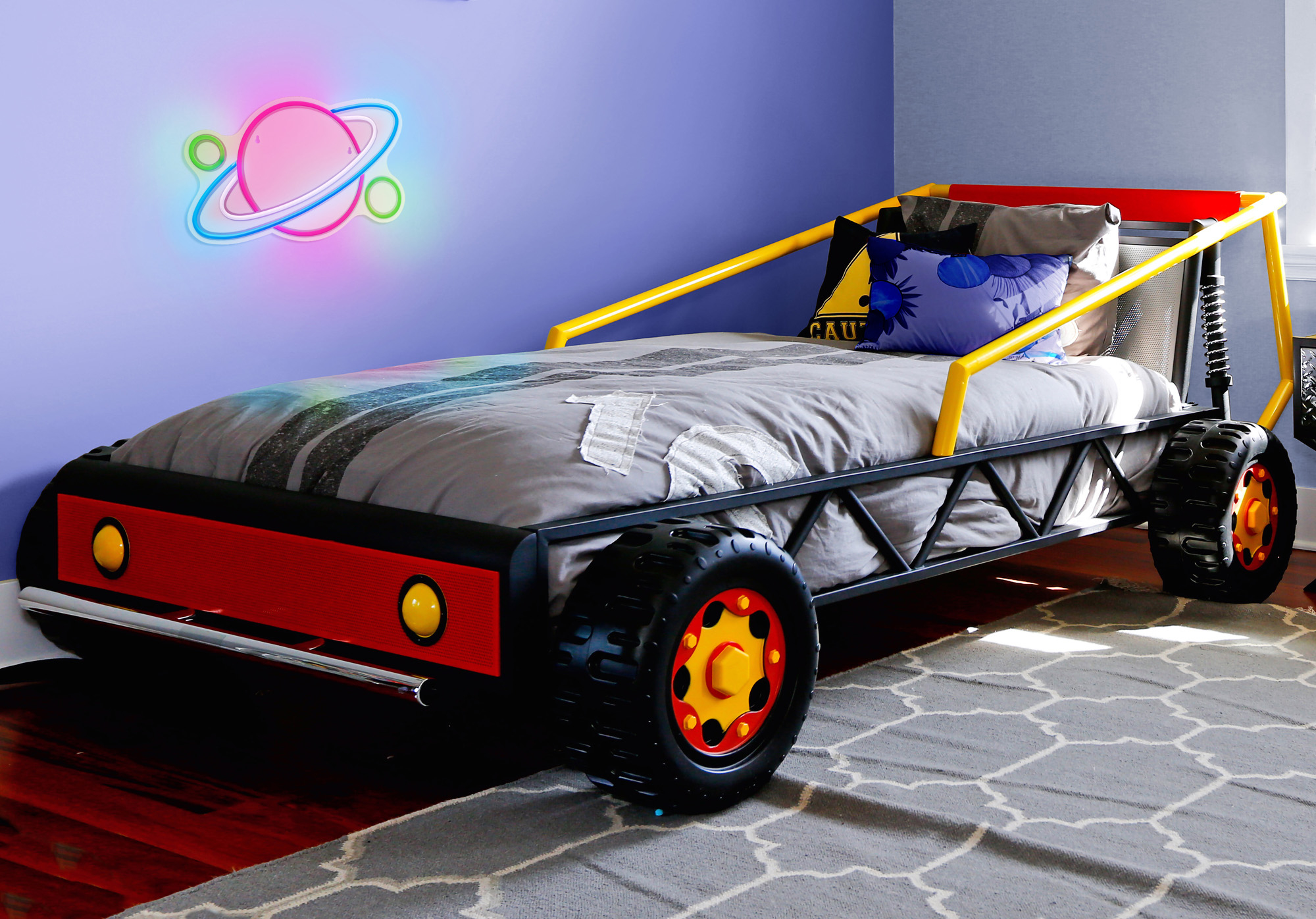 Un lit d'enfant en forme de voiture. Il est principalement rouge, noir et jaune.