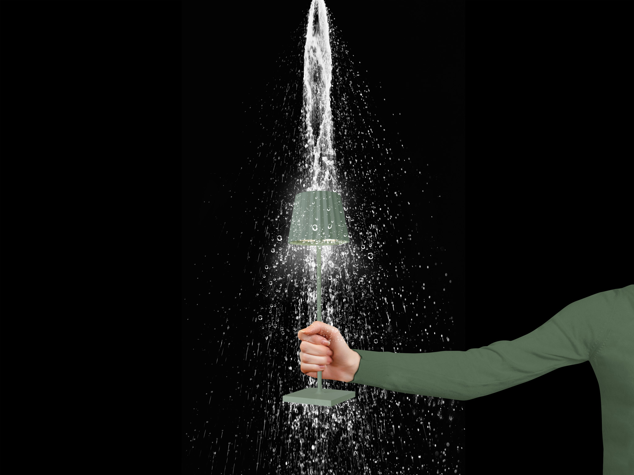 Una mano tiene una lampada con acqua che spruzza intorno, sfondo nero.
