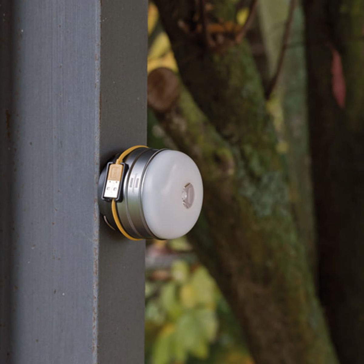USB portlu küçük, yuvarlak, beyaz LED ışık, koyu gri bir yüzeye bağlı.