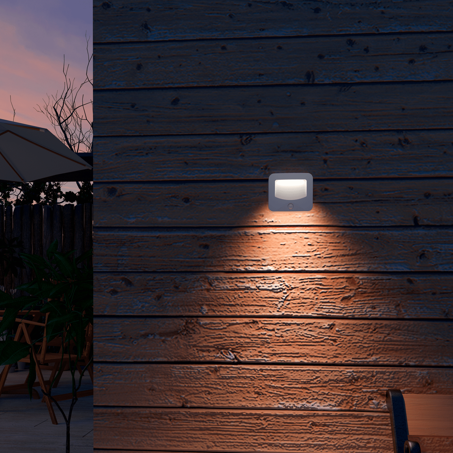 Luce esterna illuminata montata a parete su un muro di legno. Cielo serale sullo sfondo. Alberi e mobili da patio in lontananza.