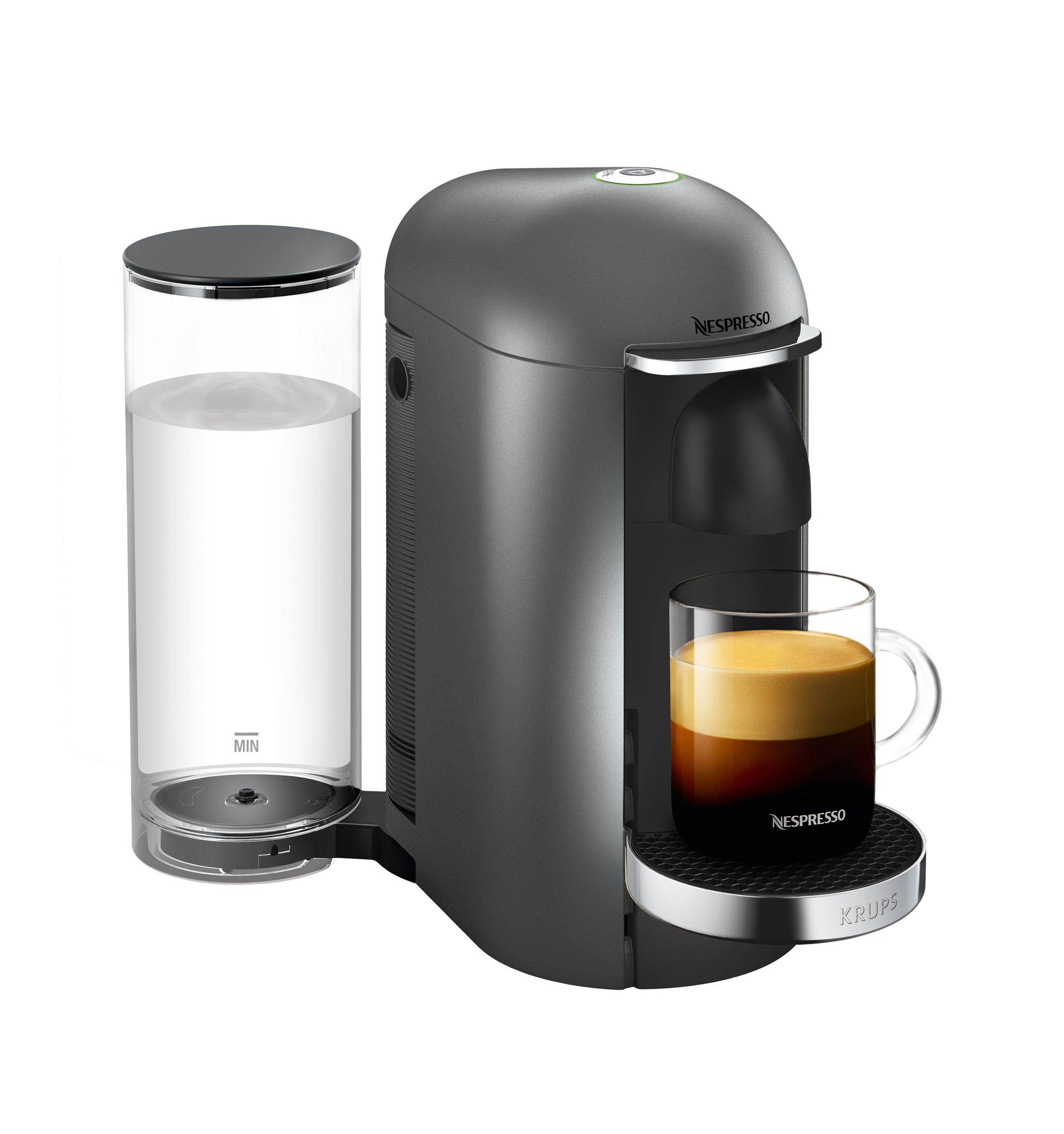 Graue Nespresso-Maschine mit einem Glas Kaffee und einem Wasserbehälter. Weißer Hintergrund.