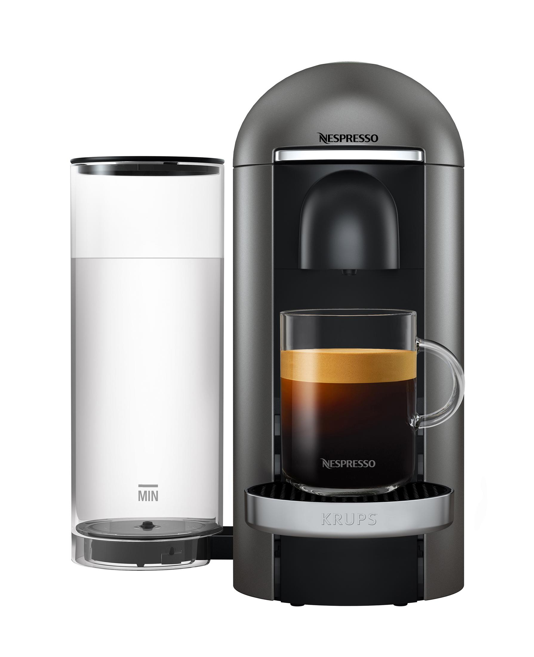 Eine graue Nespresso-Kaffeemaschine mit einer Tasse Kaffee. Ein Wassertank befindet sich links.
