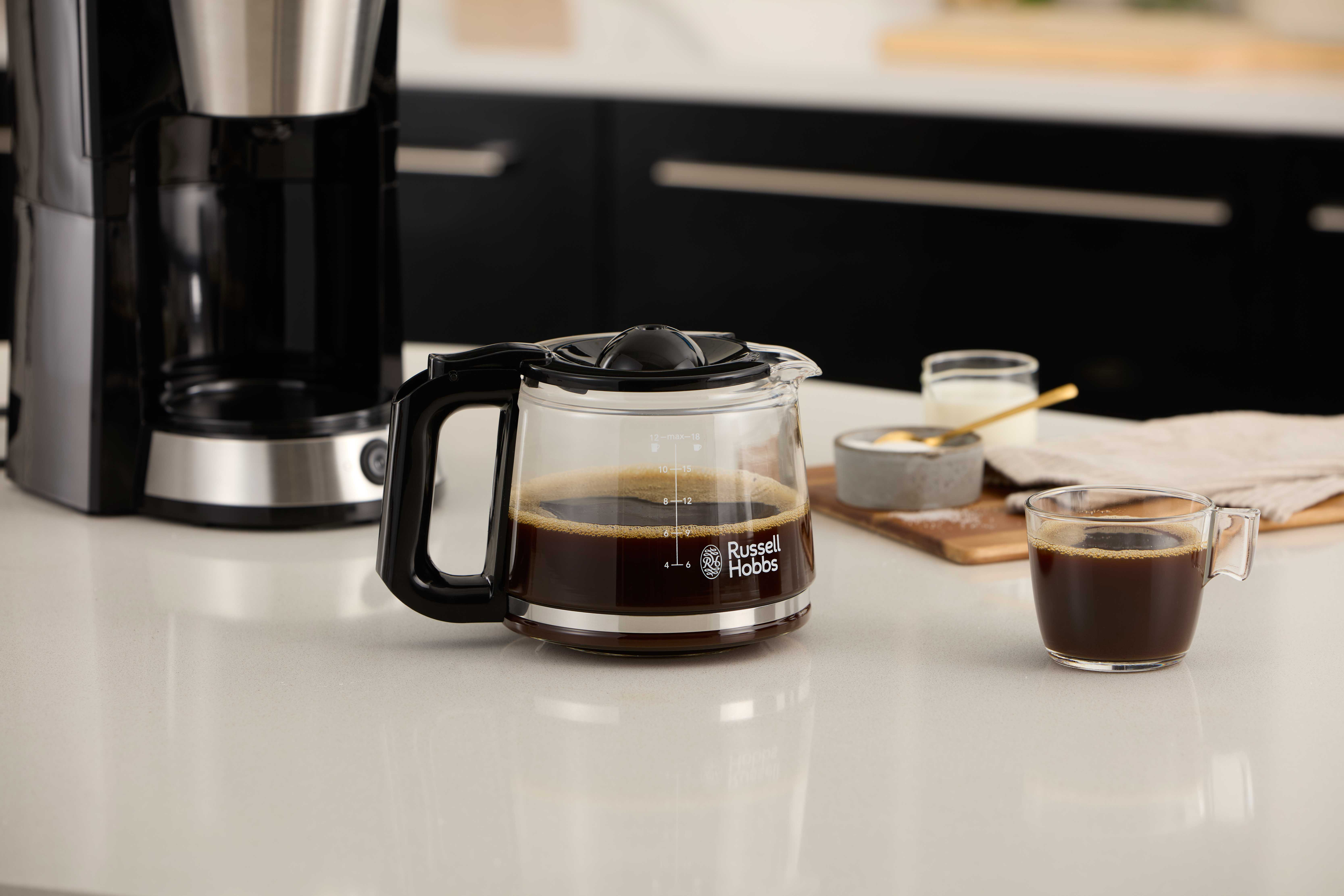 Ekspres do kawy i szklany dzbanek do kawy. Kawa w dzbanku. Filiżanka i mleko na stole.