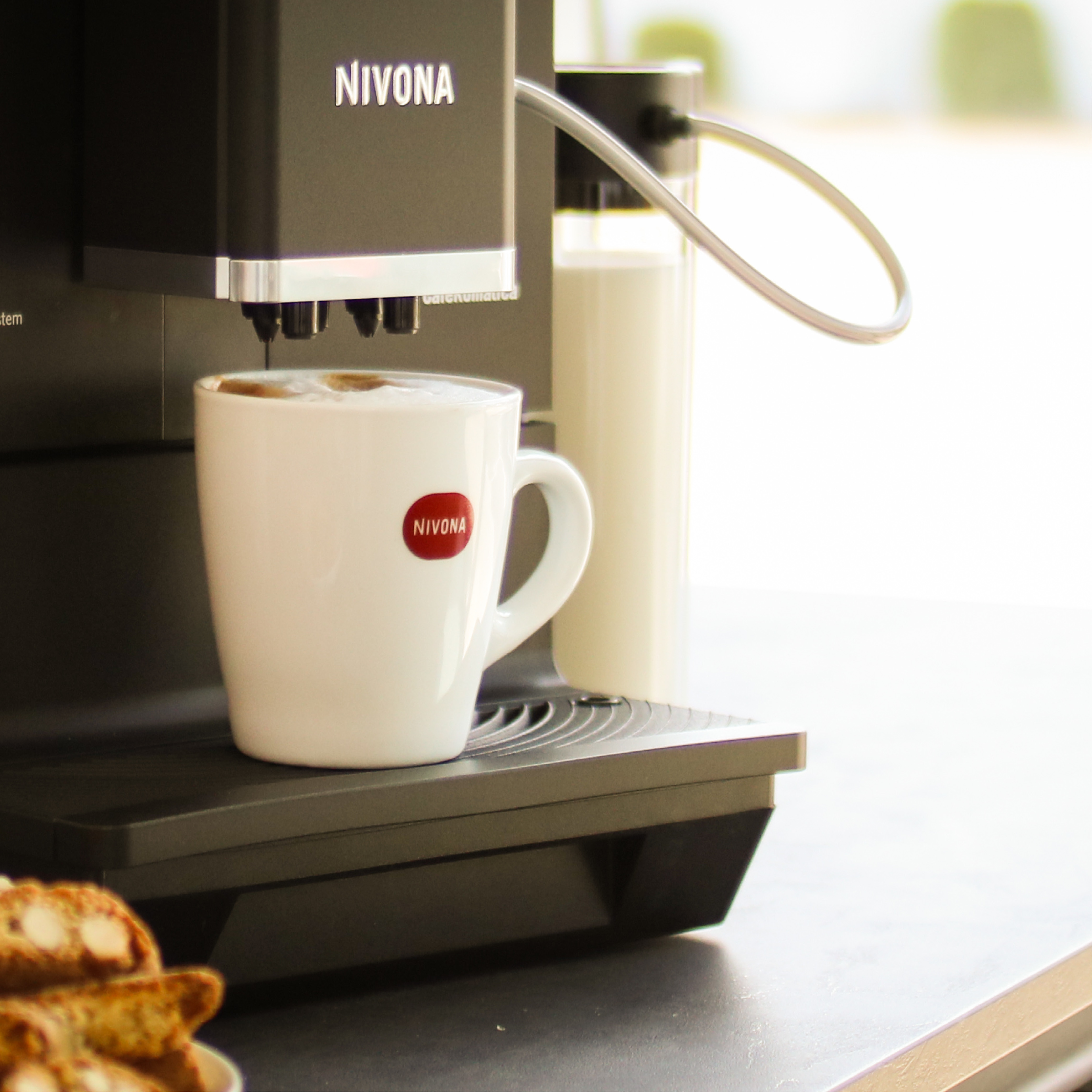 Macchina da caffè che eroga caffè in una tazza bianca con logo.