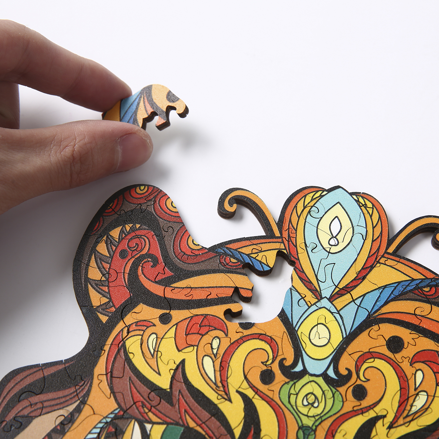 Eine Hand setzt ein Puzzleteil ein. Das Puzzle hat ein farbenfrohes Design.