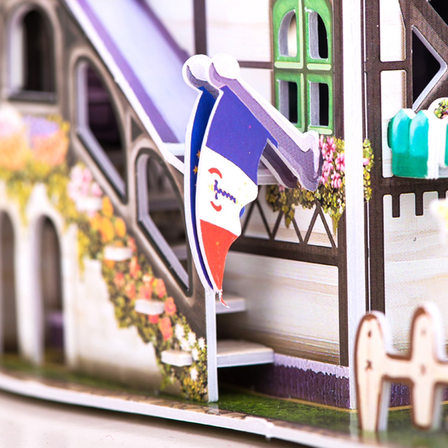 Un modello di casa bianca con bandiera francese. Sono visibili anche fiori, scale e finestre.