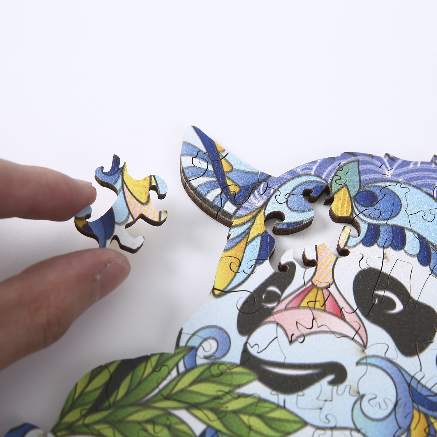 Una mano che tiene un pezzo di puzzle, accanto a un puzzle di panda. Sfondo bianco.