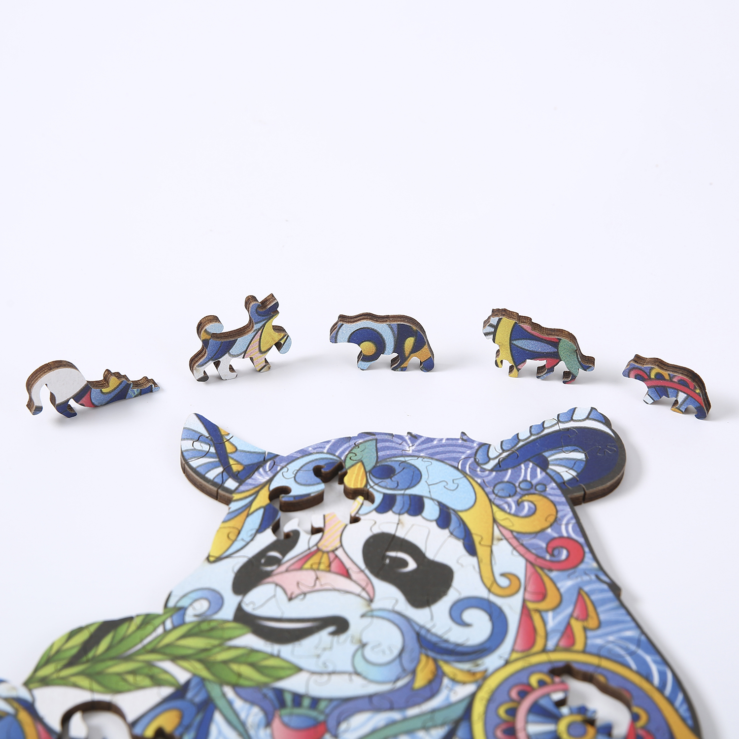 Pezzi di puzzle in legno a forma di animali colorati sparsi su una superficie bianca.