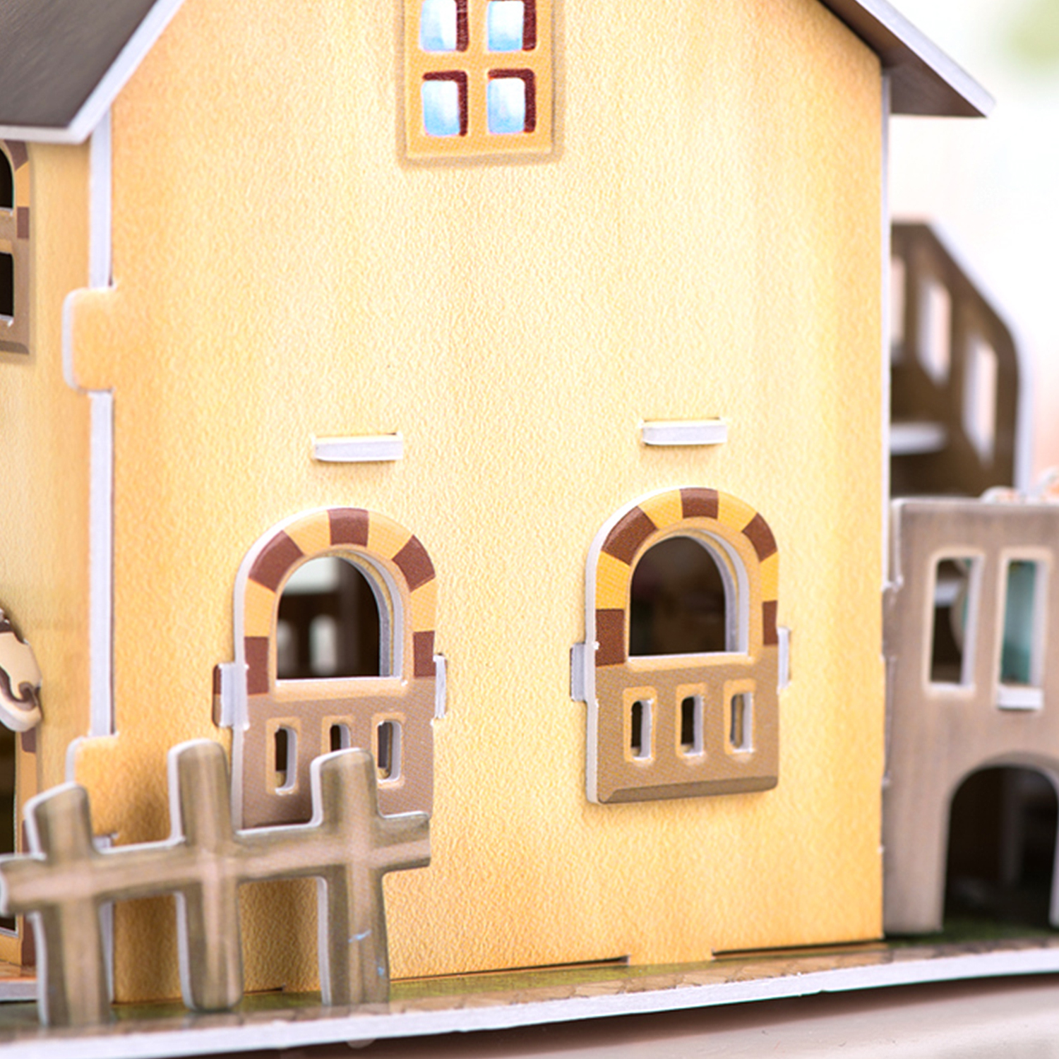 Un modello in miniatura di una casa gialla con una staccionata e finestre ad arco.