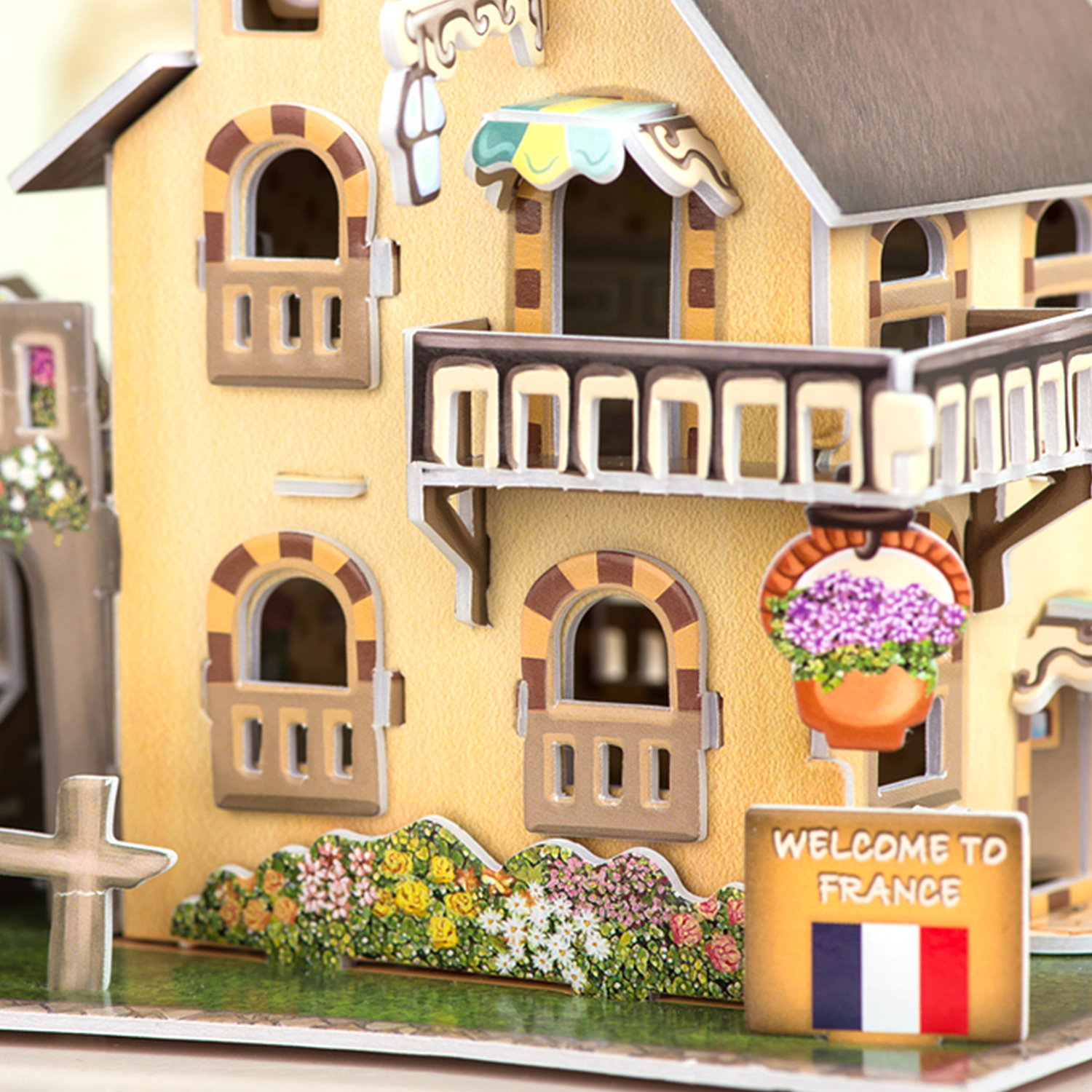 Un modello 3D di una casa gialla con un balcone e un cartello con scritto 'Welcome to France'.