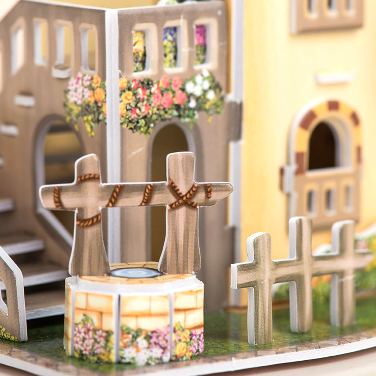 Miniatura di puzzle 3D di un villaggio europeo con un pozzo e due croci in primo piano.