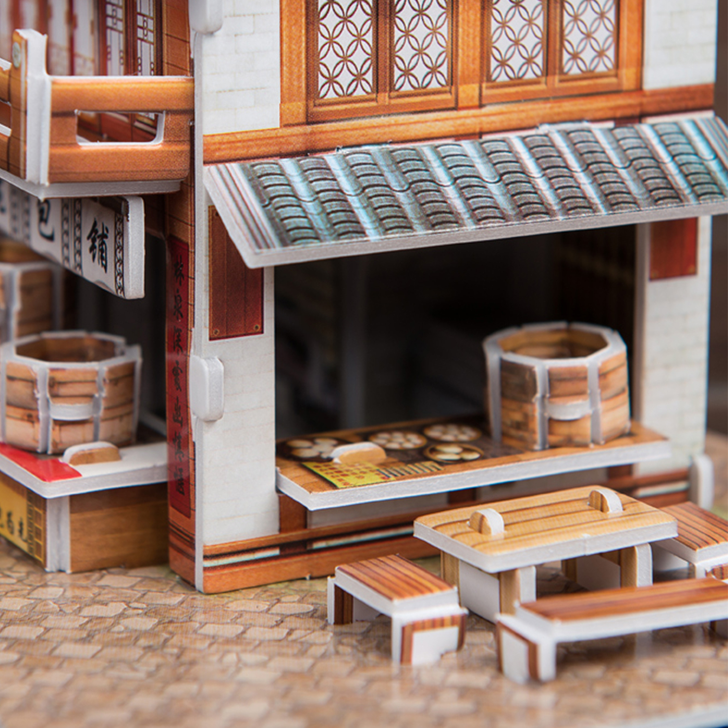 Un negozio artigianale di carta in miniatura con tavoli, strutture in legno e pavimento piastrellato.