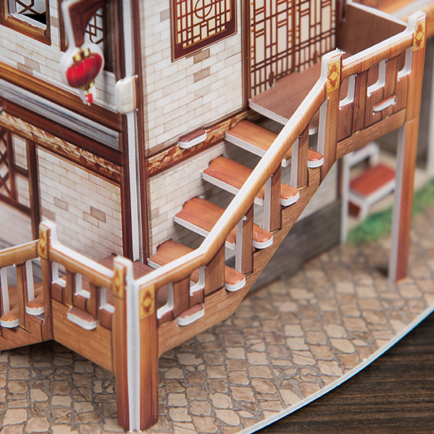 Modello in legno di una casa con scale e ringhiera. Lanterne rosse appese al tetto. Pavimento lastricato.