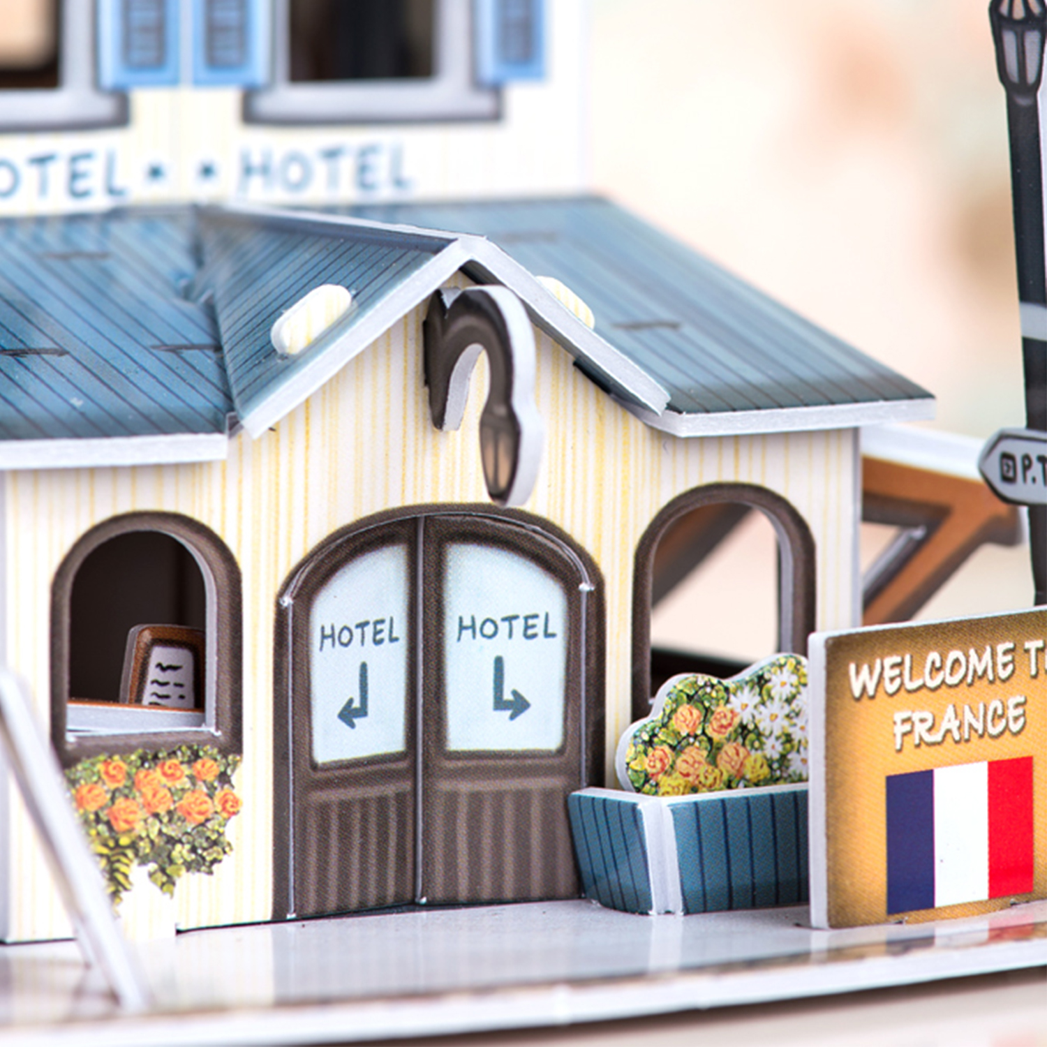 Ein Miniatur-Hotelmodell mit einem Schild mit der Aufschrift Willkommen in Frankreich. Es gibt Blumen.