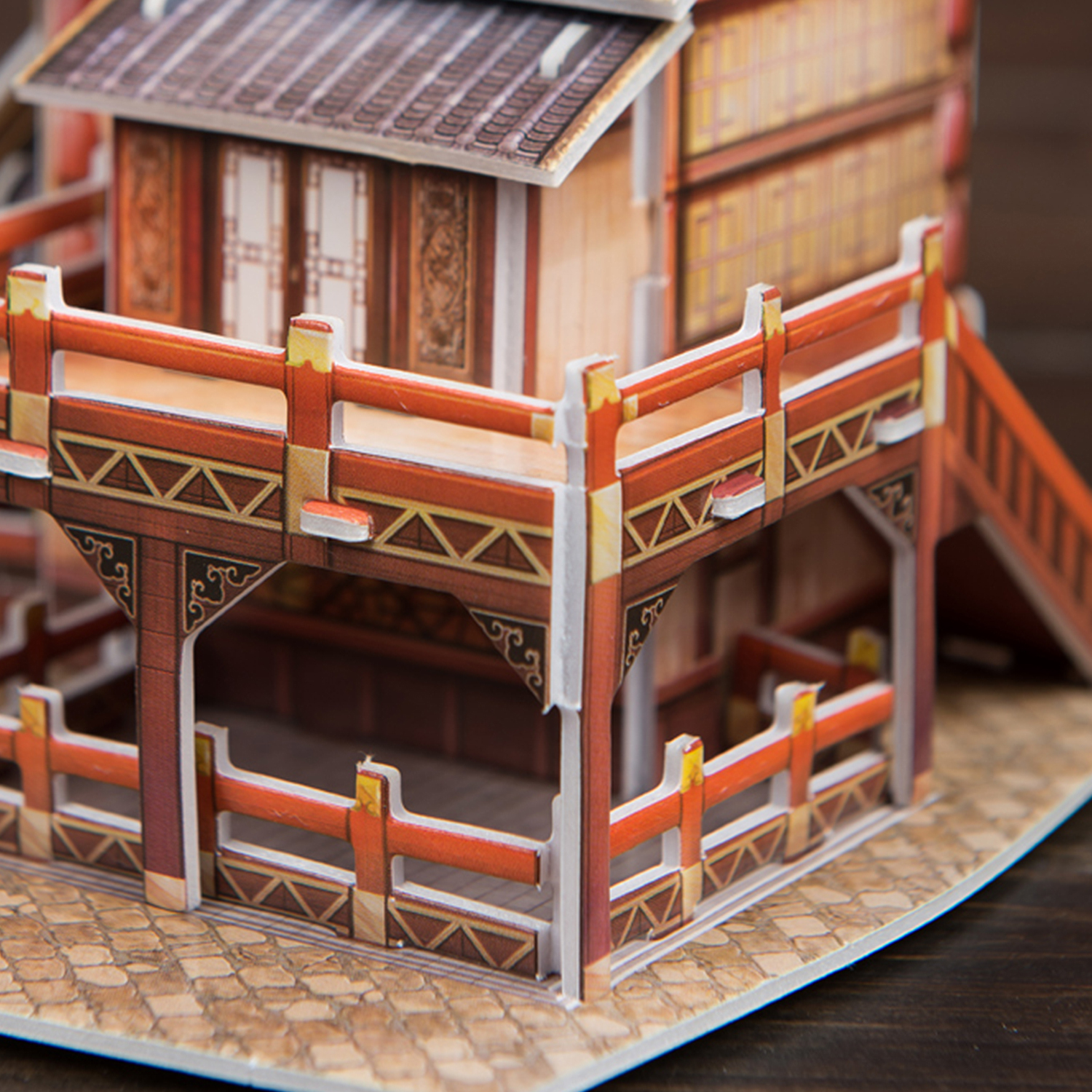 Modell eines chinesischen Gebäudes mit roten und orangen Details auf Holzoberfläche.