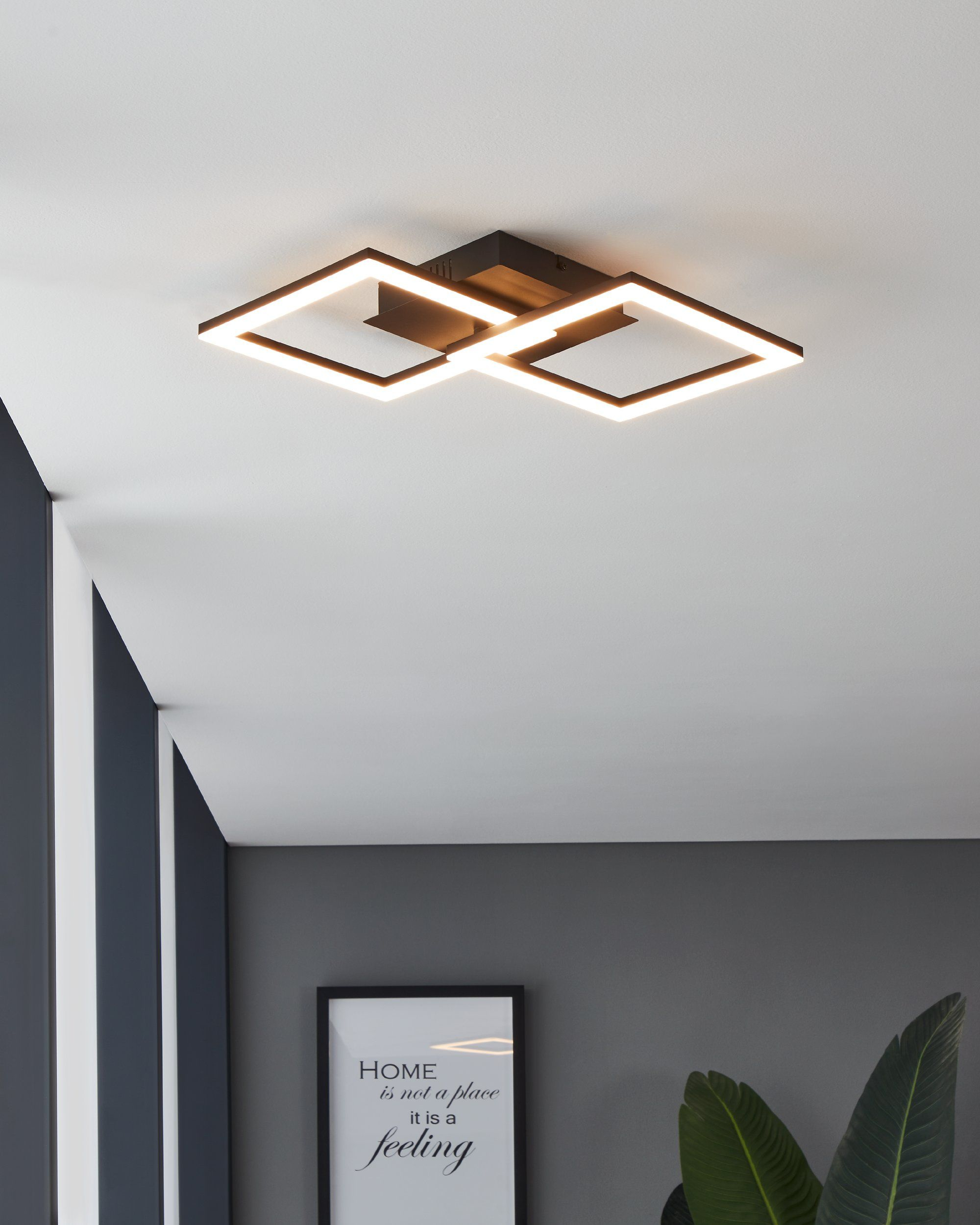 Una lampada da soffitto con due luci quadrate è mostrata contro un muro scuro.