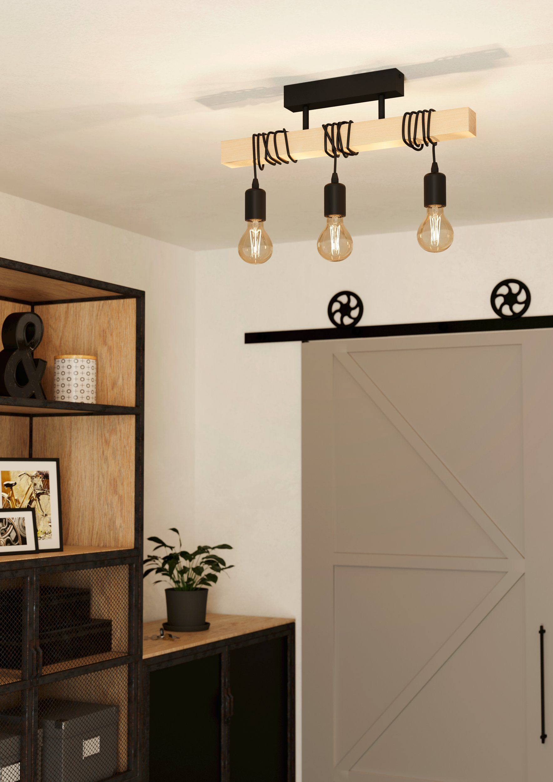 Intérieur avec un plafonnier en poutre de bois et trois ampoules apparentes suspendues.