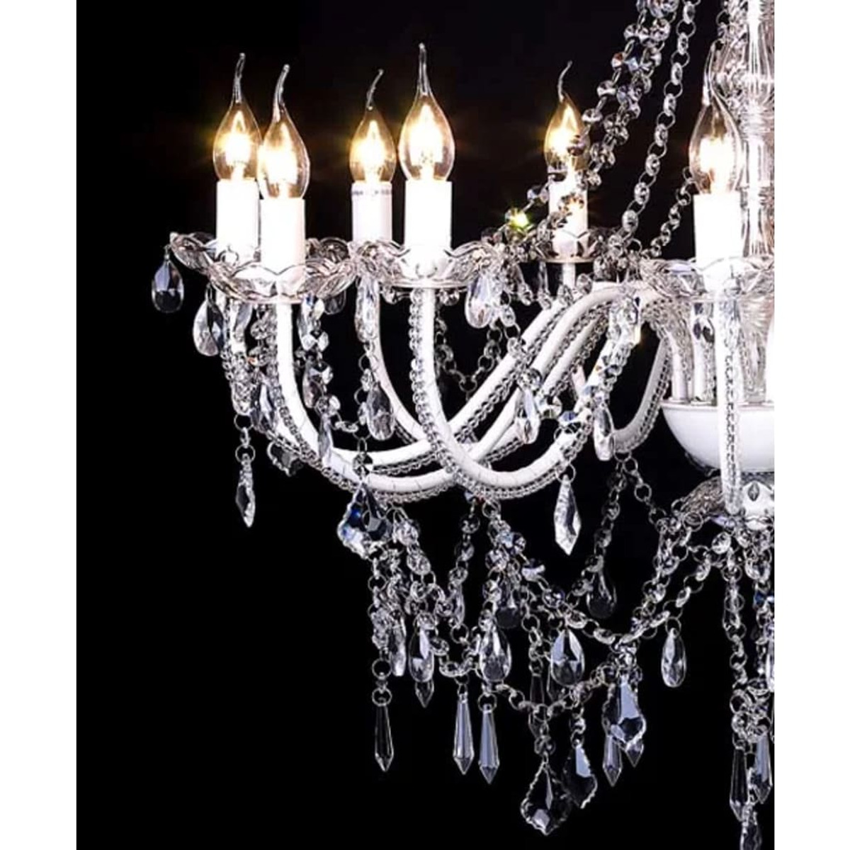 Lampadario bianco con cristalli pendenti e lampadine a forma di candela accese su sfondo nero.