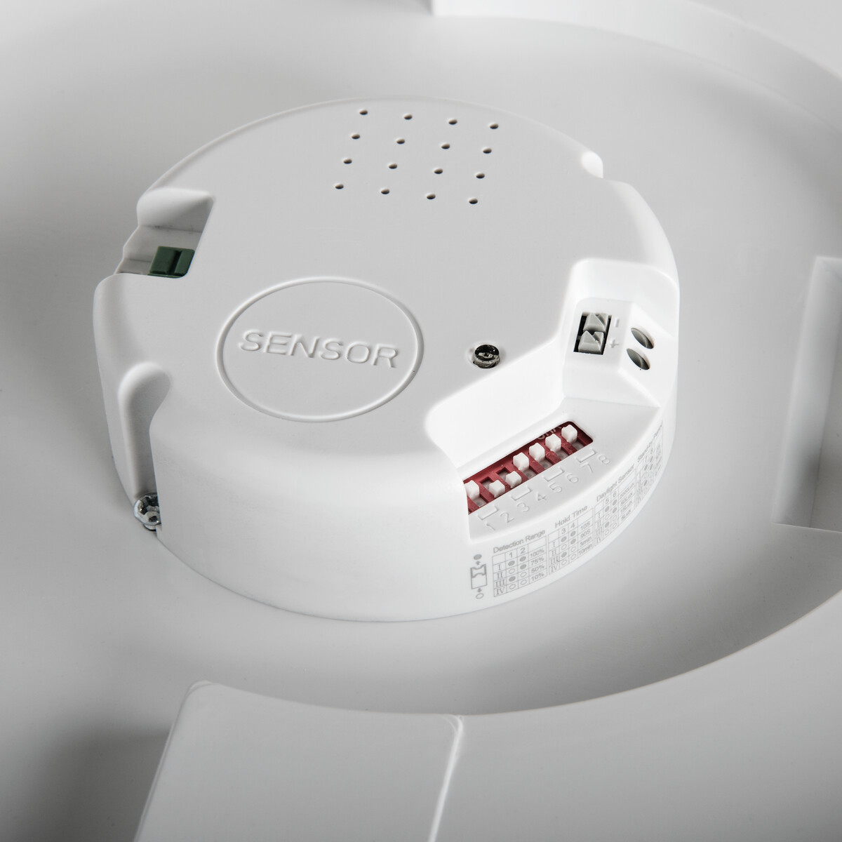 Un componente sensor blanco con secciones etiquetadas e interruptores rojos.
