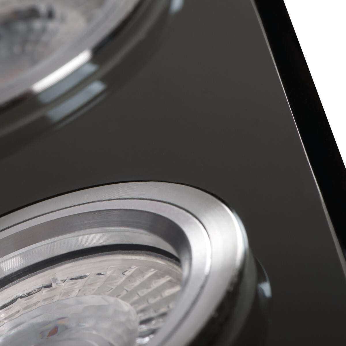 Close-up van inbouwverlichtingsarmaturen met een zwart oppervlak en zilveren armaturen.