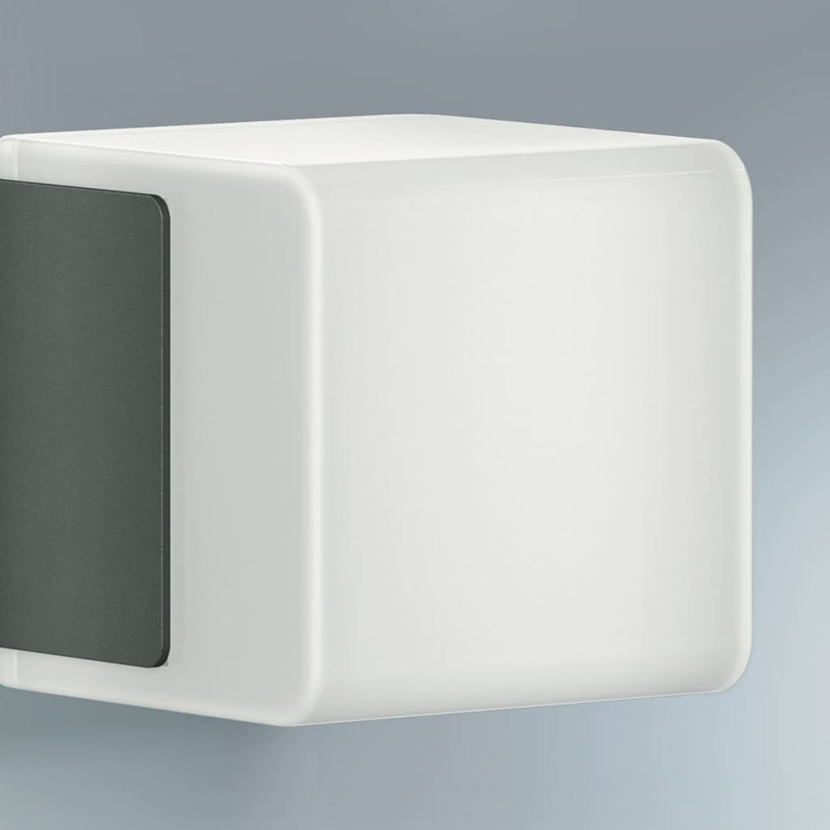 Un apparecchio di illuminazione esterno bianco a forma di cubo montato su un muro grigio chiaro.