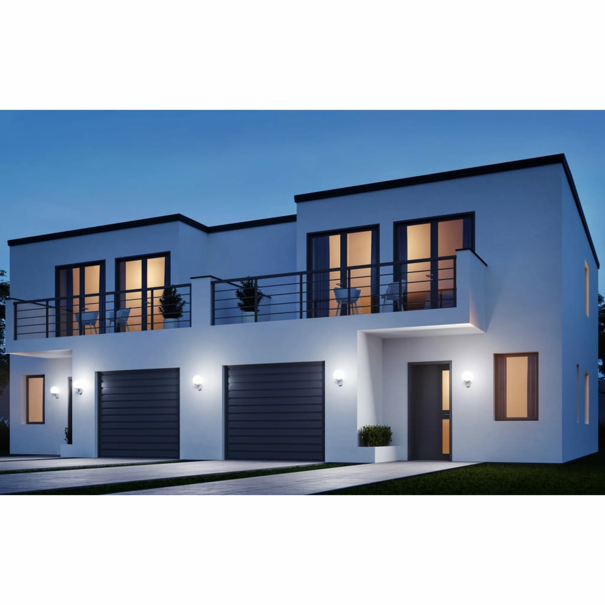 Moderne zweistöckige weiße Häuser in der Abenddämmerung, mit Lichtern, Garage und dunkelblauem Himmel.
