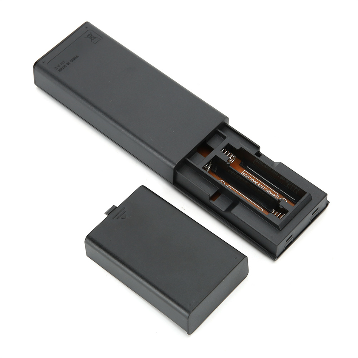 Geöffnete Fernbedienung mit Batterien und abgenommener Batterieabdeckung auf weißer Oberfläche.