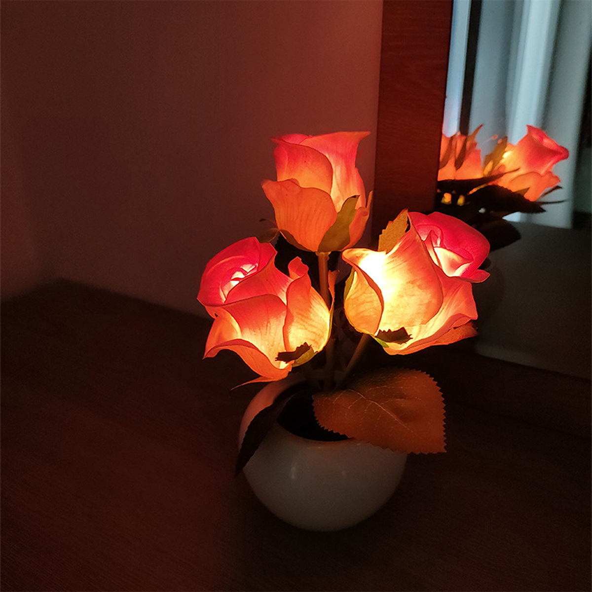 Beleuchtete künstliche Rosen in weißer Vase. Der Raum ist schwach beleuchtet.