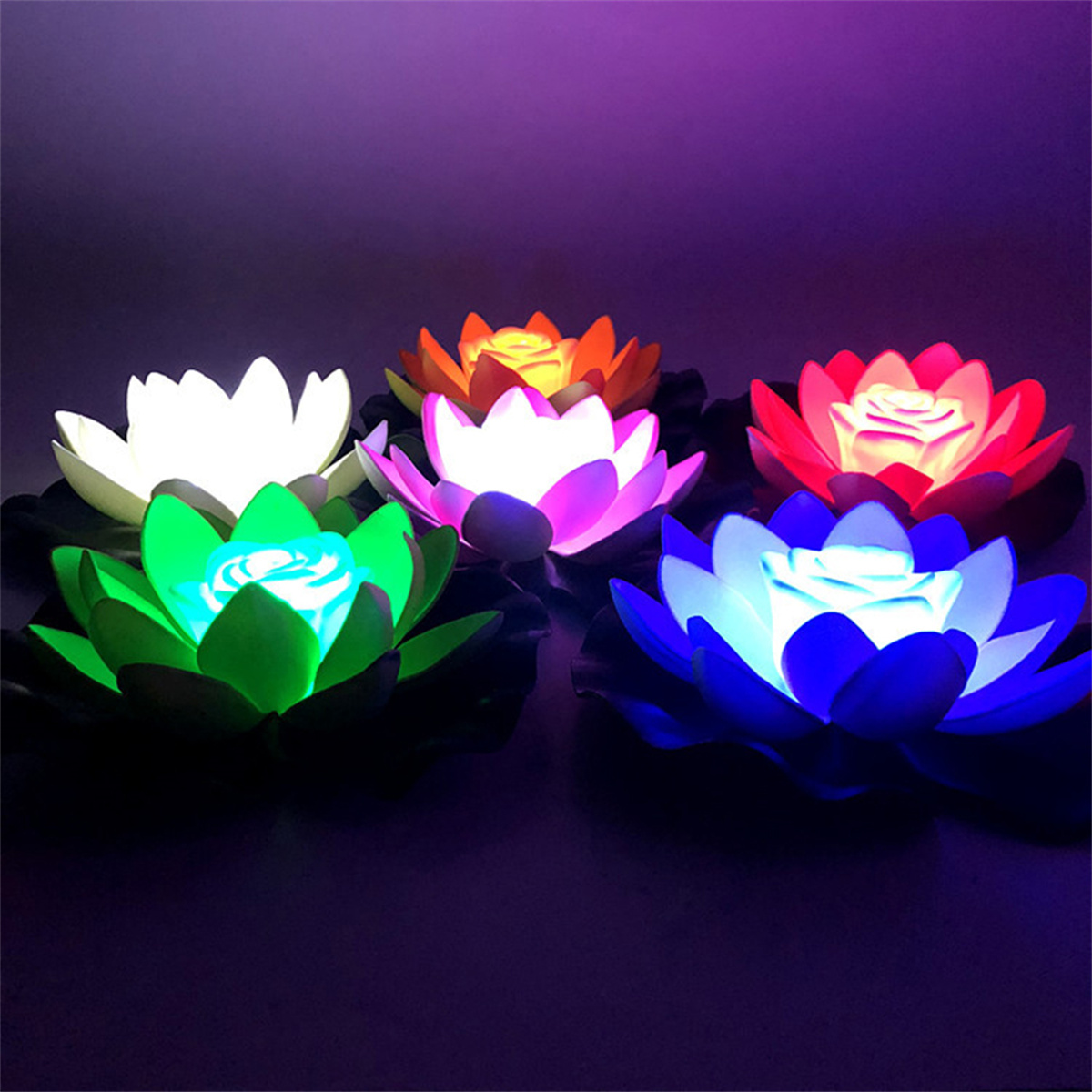Mehrere bunte, schwimmende Lotusblumenlichter auf dunklem Hintergrund. Jede Blume hat ein zentrales Licht.