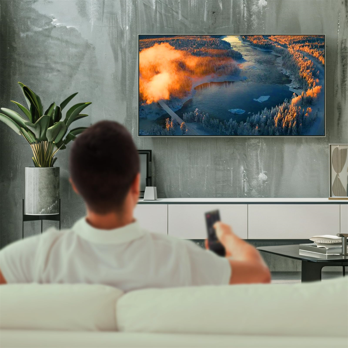 Eine Person schaut fern mit Fernbedienung; der Fernseher zeigt eine Winterlandschaft.