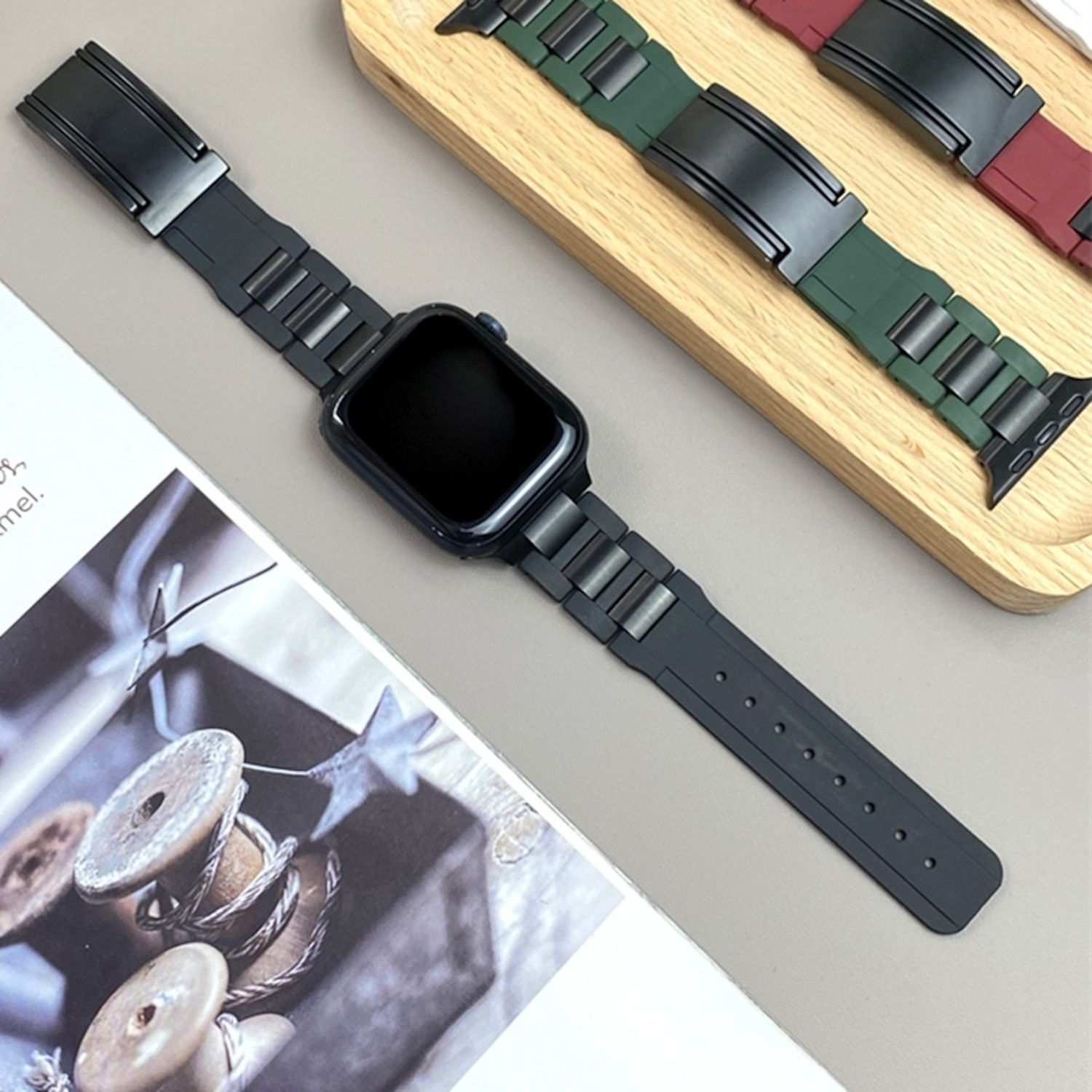 Eine schwarze Uhr mit schwarzem Armband und ein paar Uhrenarmbändern auf einem Holzbrett.