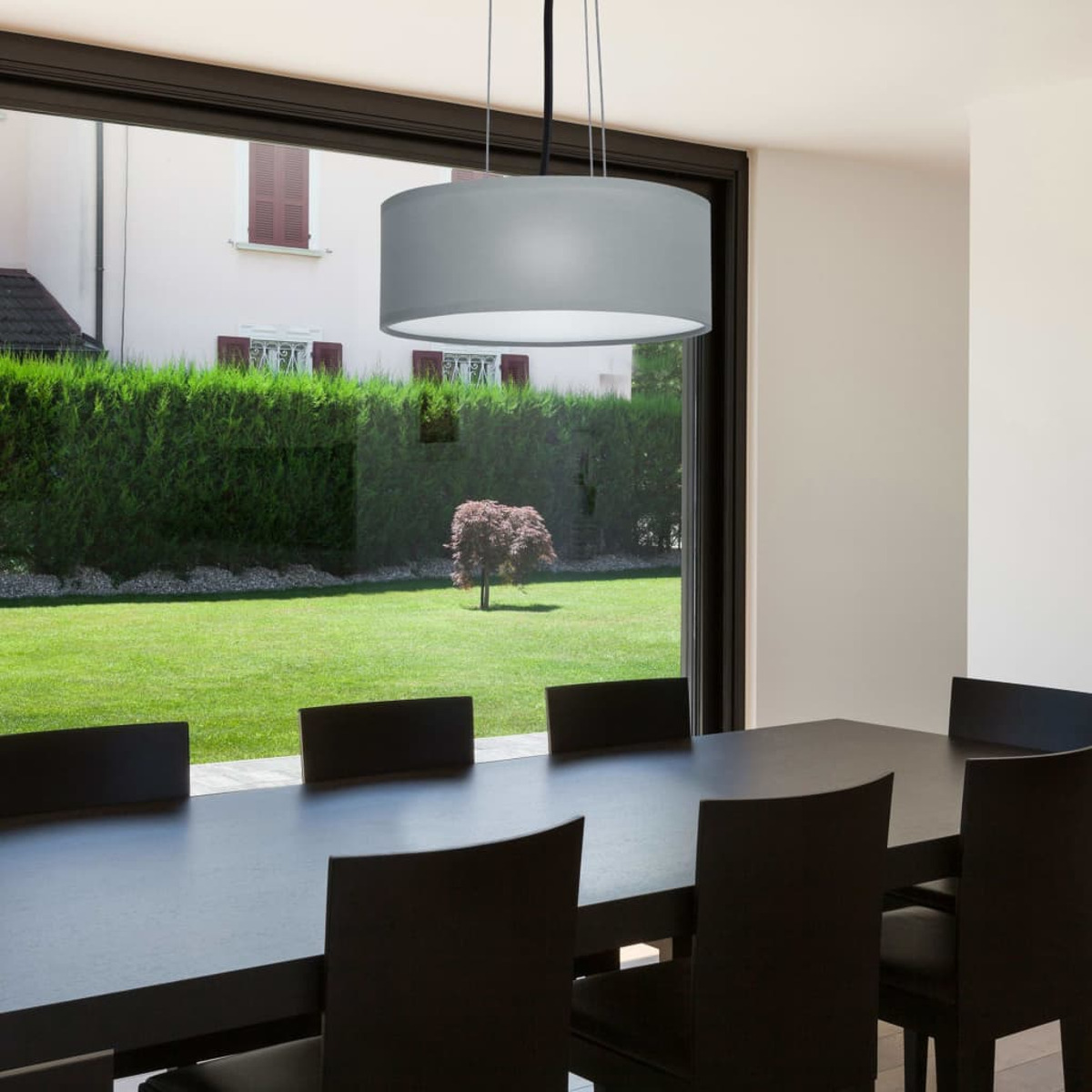 Scena di sala da pranzo con lampadario e una grande finestra con giardino.