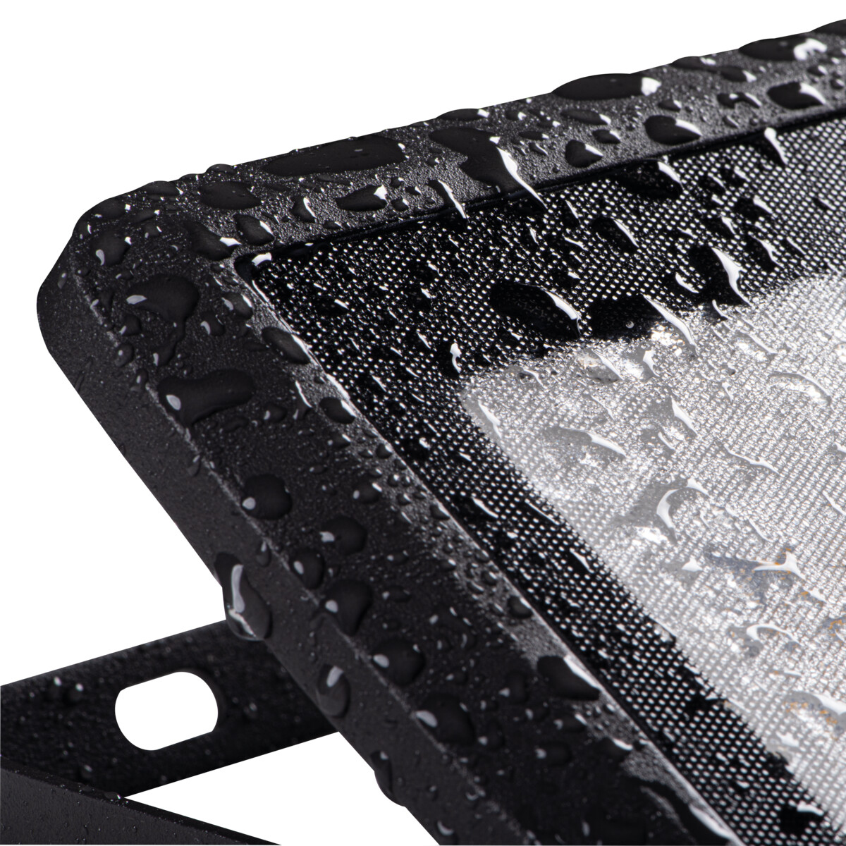 A close-up of a black floodlight with water droplets on its surface. The light is off.