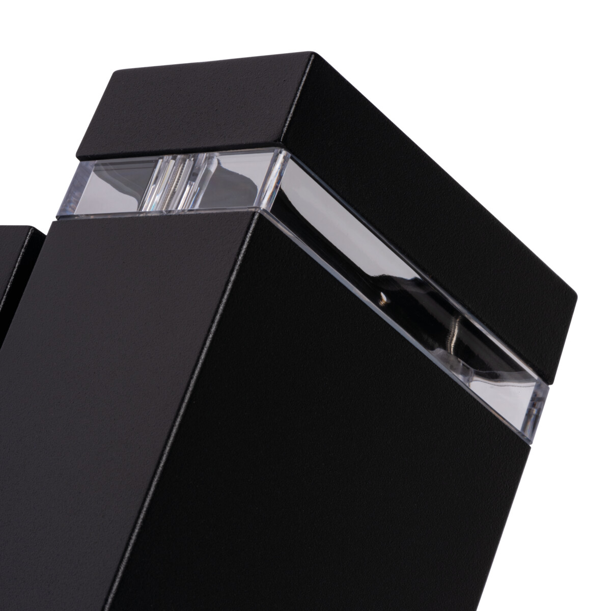 Close-up of black, angled light fixture with transparent panels. White background.