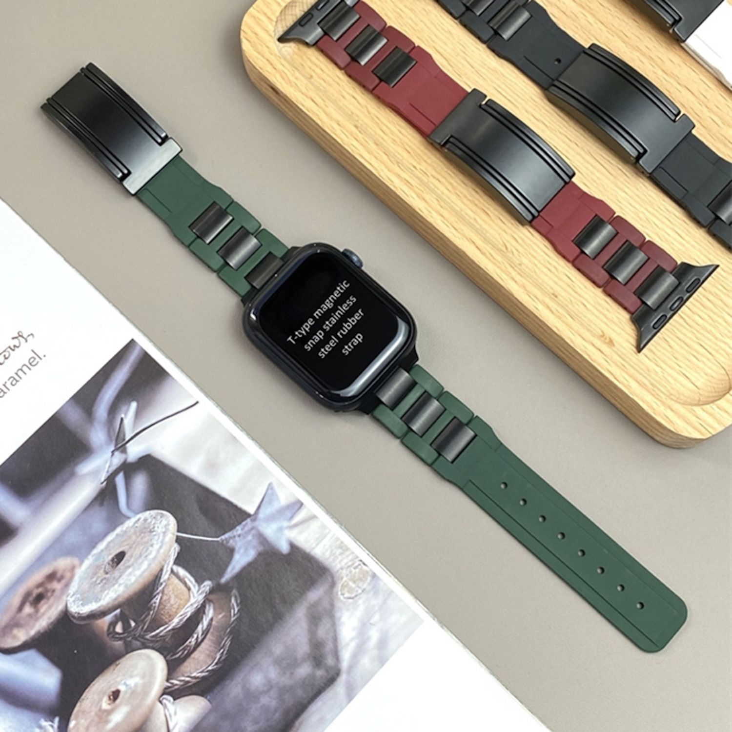 Grünes Apple Watch-Armband auf einem Holztablett. Andere Armbänder befinden sich im Hintergrund.