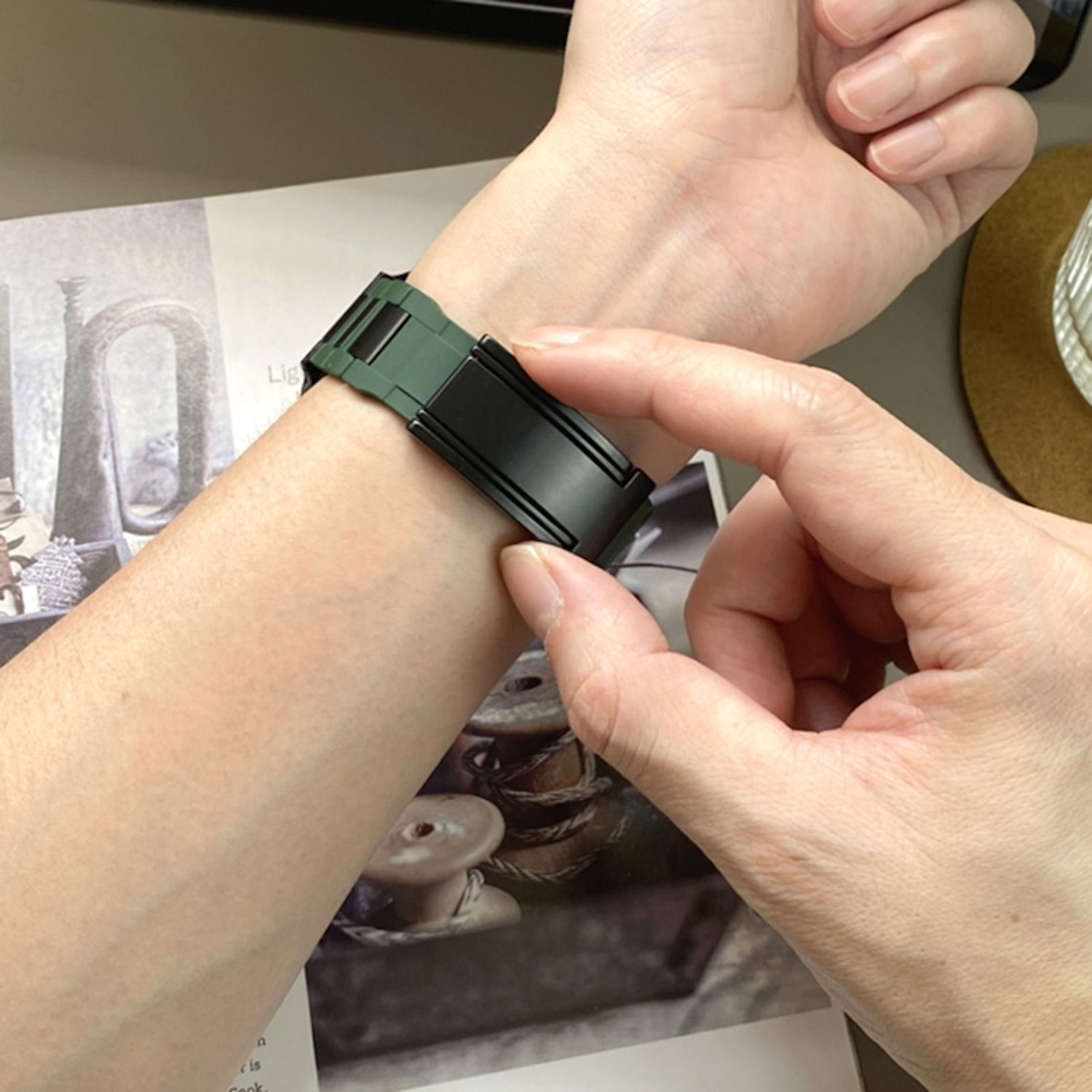 Die Hand einer Person mit einer Uhr am Handgelenk. Das Uhrenarmband ist grün und schwarz.