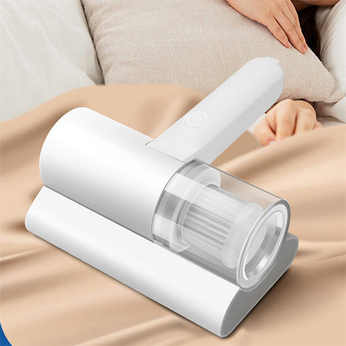 Weißer Handstaubsauger auf einem Bett. Eine Hand ruht im Hintergrund.
