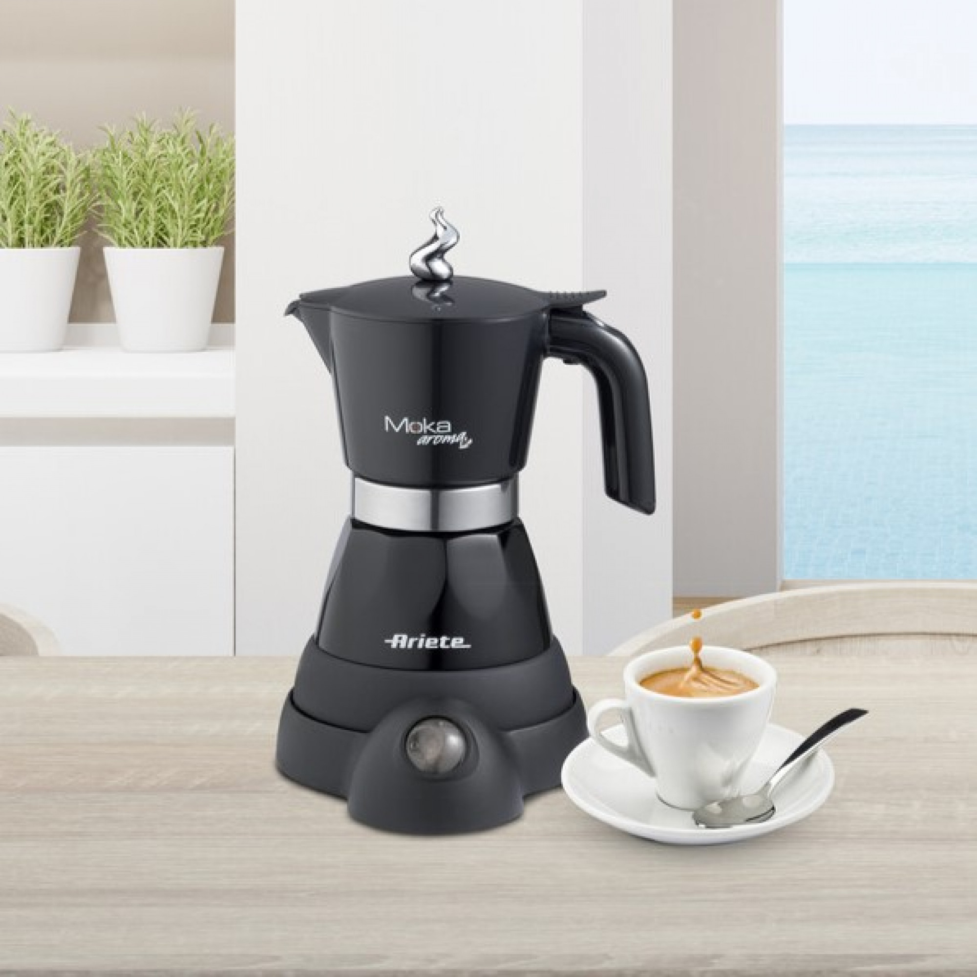 Schwarze Moka Aroma Kaffeemaschine mit einer Tasse Kaffee auf einem Holztisch, mit Strandblick.