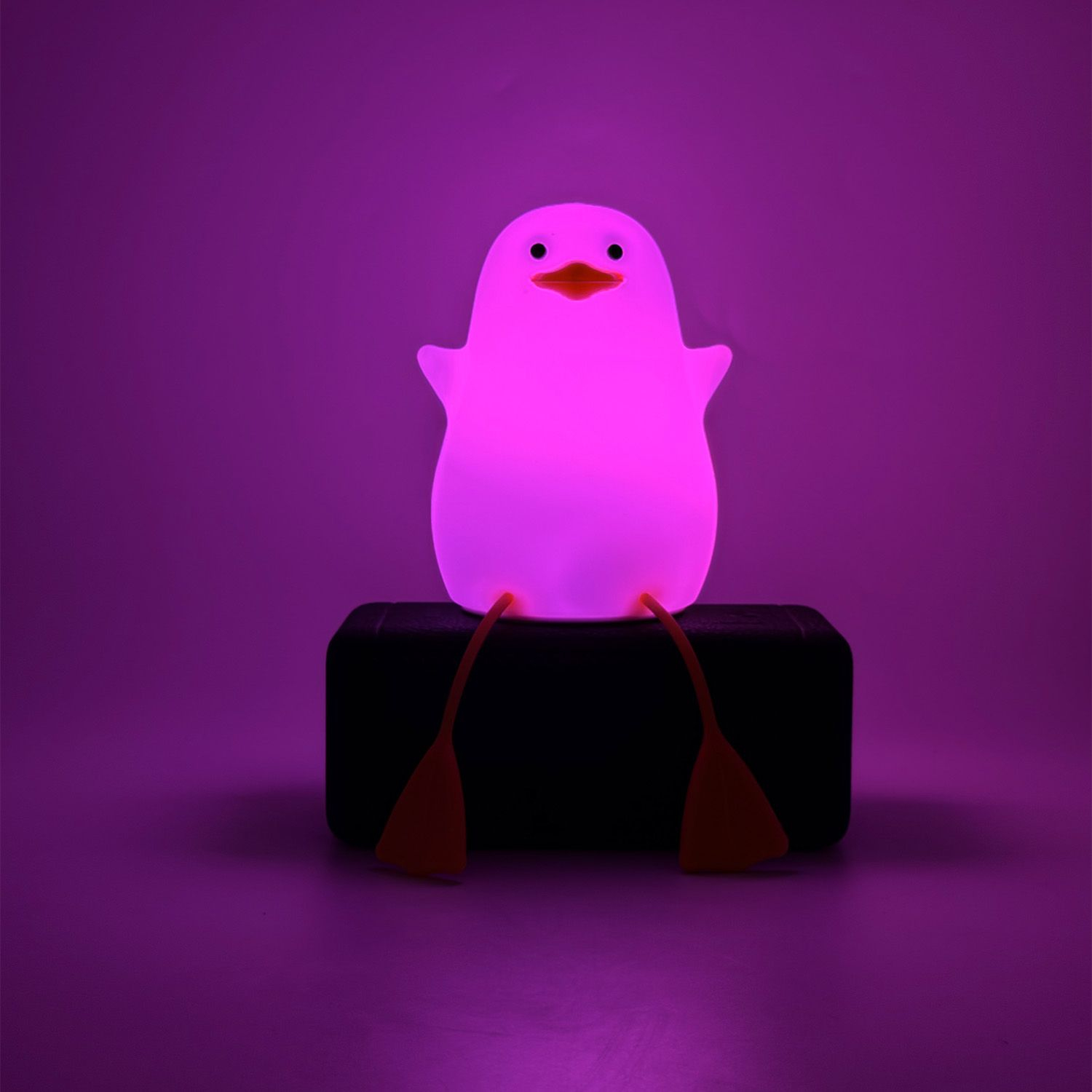 Una lampada a forma di pinguino rosa. La lampada è seduta su una base nera in una stanza rosa.