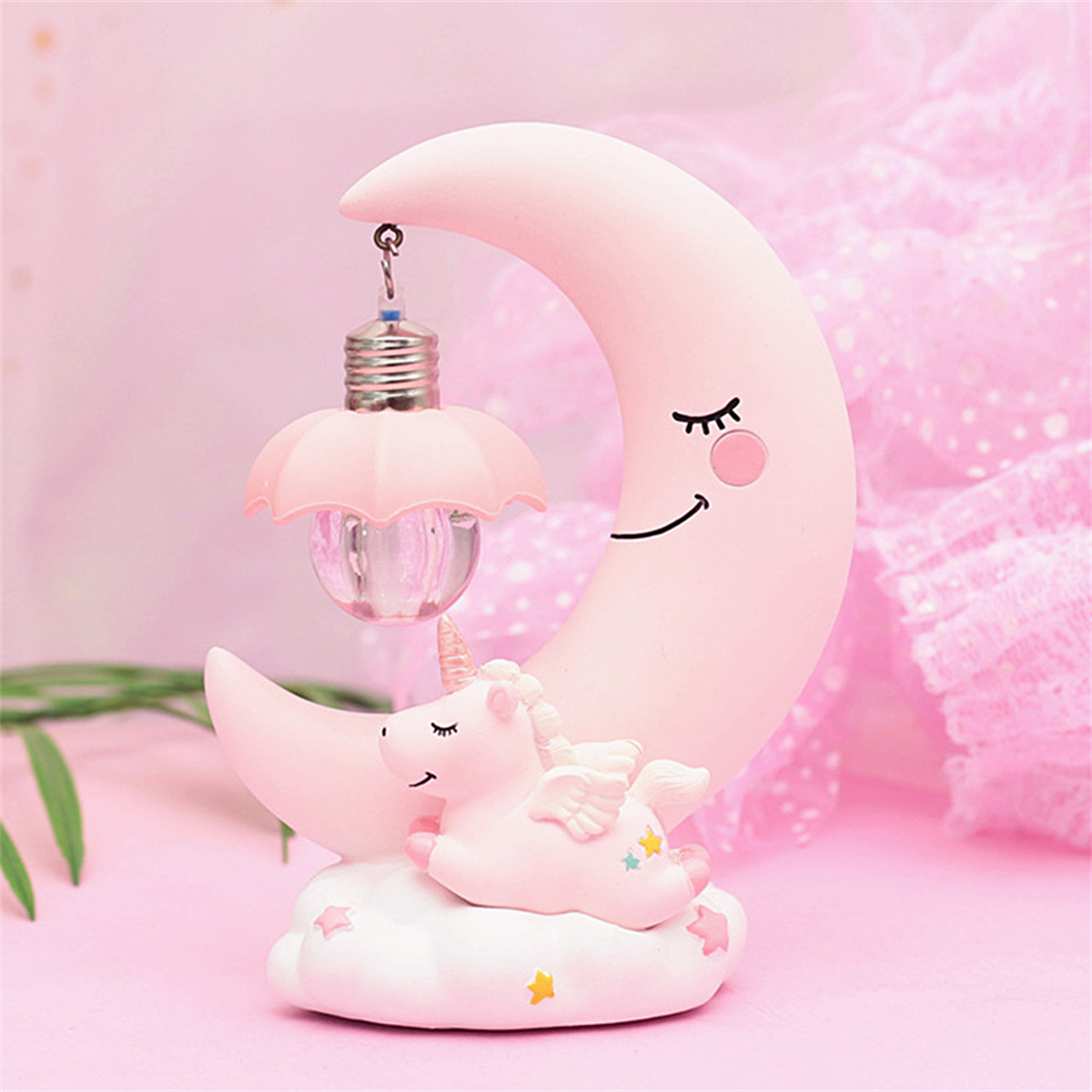 Rosa Halbmond mit schlafender Einhorn-Lampe auf rosa Oberfläche.