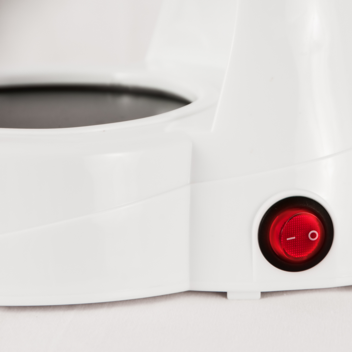 Zbliżenie białego urządzenia z czerwonym przyciskiem zasilania.