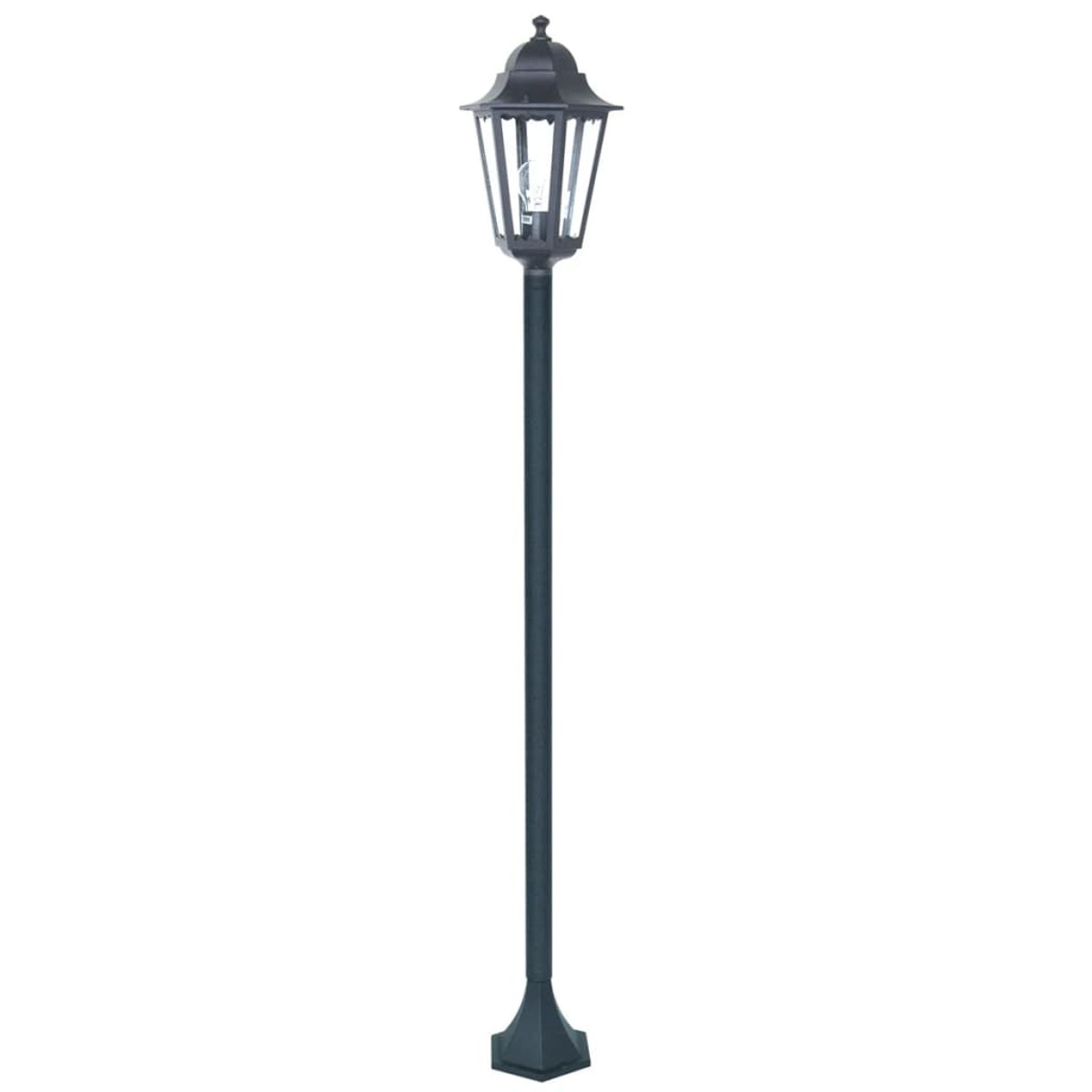 Un lampione nero, ornato, su un palo. La luce è in cima, con uno sfondo chiaro.