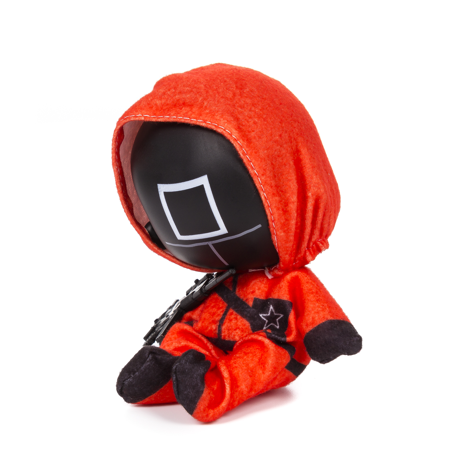 Un peluche di un personaggio di Squid Game, in tuta arancione, maschera nera, sfondo bianco.